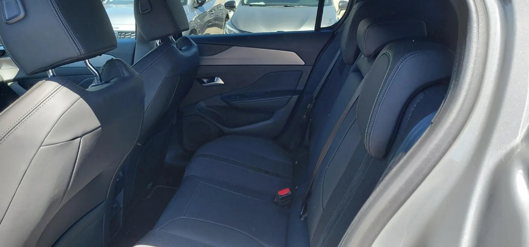 Vue intérieure côté droit des sièges arrière noirs avec surpiqûres vertes d'une Peugeot 308 Hybrid 145 e-DCS6 GT gris 2025.