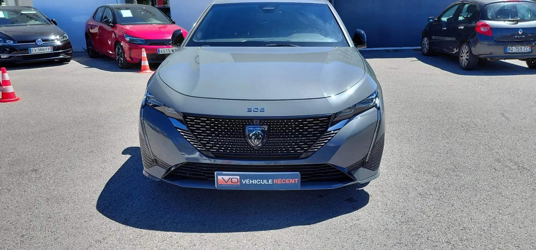 Vue avant d'une Peugeot 308 Hybrid 145 e-DCS6 GT gris métallisé avec calandre noire et logo lion central.