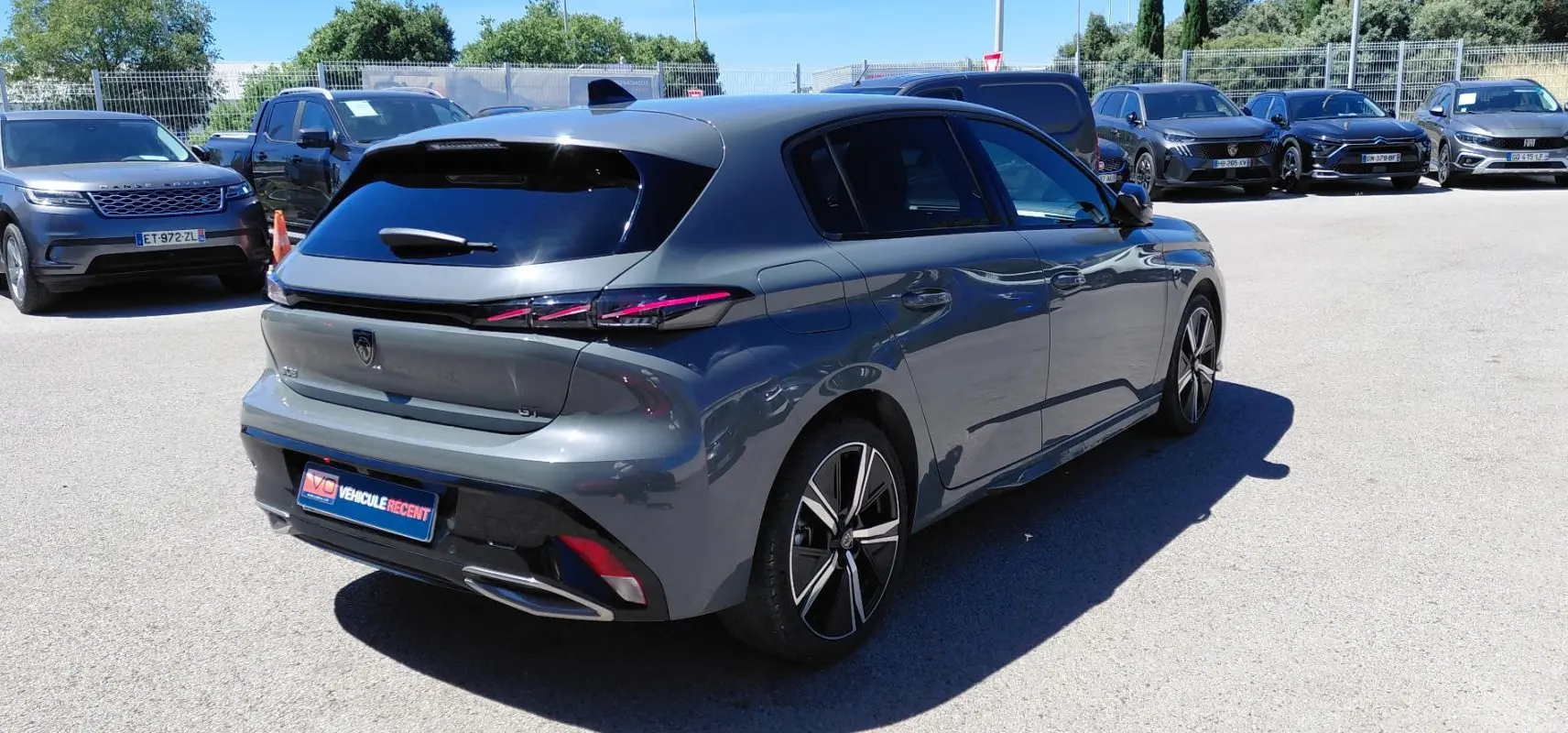 Vue 3/4 arrière droit d’une Peugeot 308 Hybrid 145 e-DCS6 GT gris avec jantes alliage 18 pouces et feux arrière LED distinctifs.