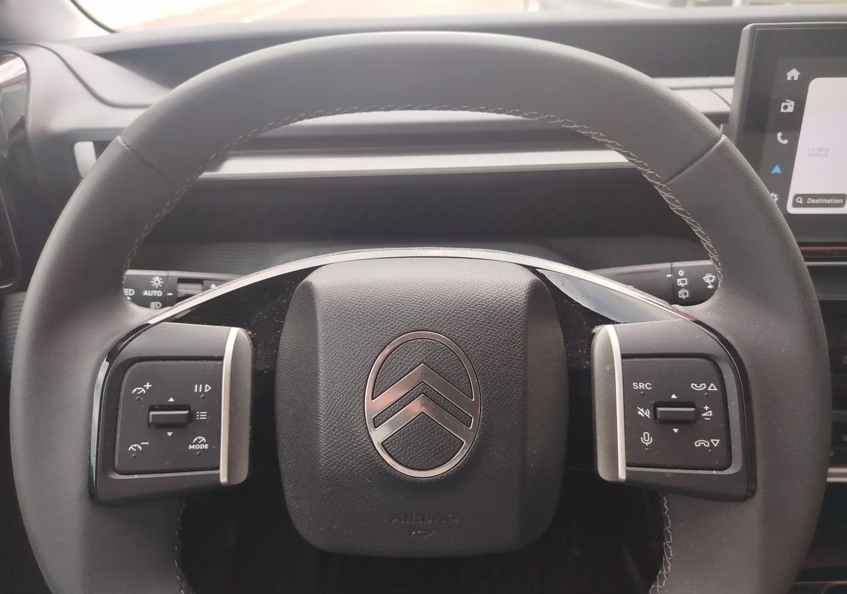 Vue rapprochée du volant noir avec logo Citroën argenté et commandes intégrées du tableau de bord d'une C3 2025.
