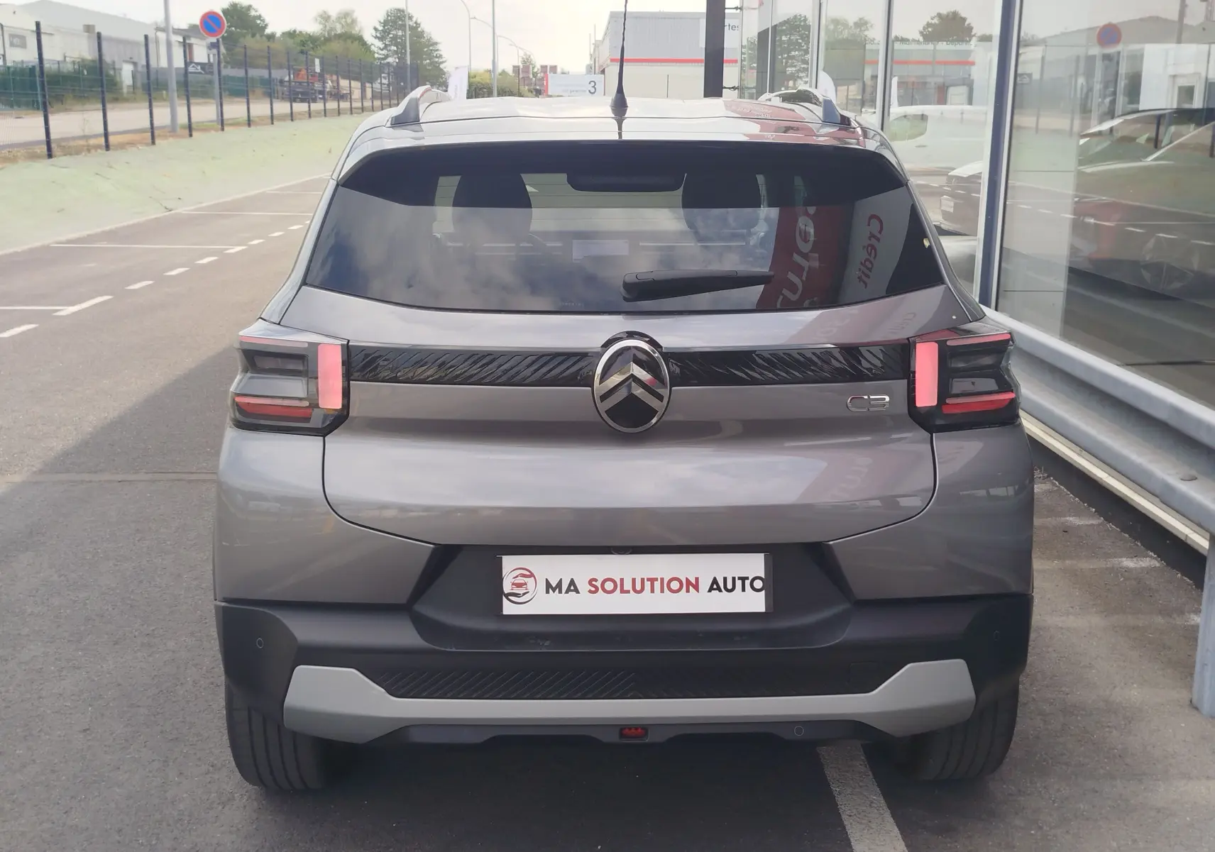 Vue arrière d'une Citroën C3 2025 gris foncé avec toit noir, feux arrière LED et logo central chromé.