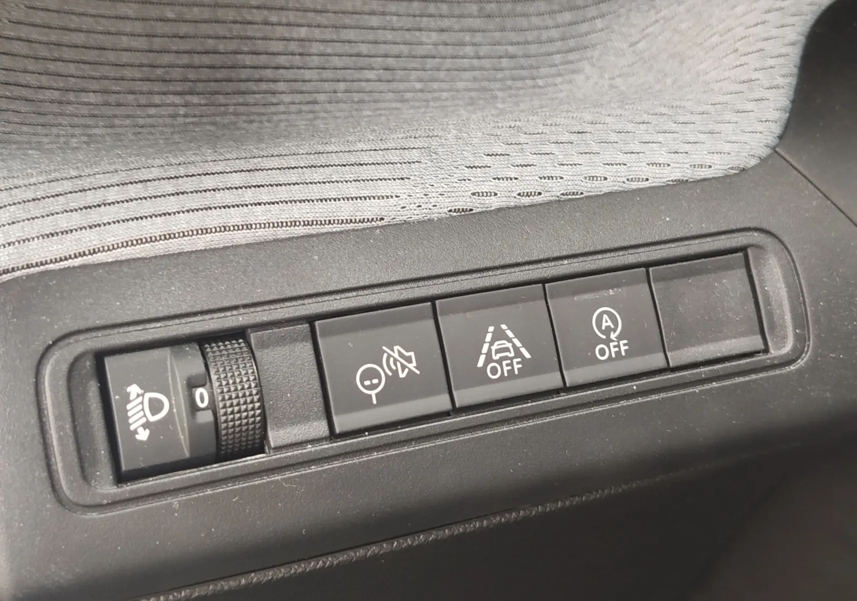 Vue rapprochée des commandes de réglage des phares et des aides à la conduite sur une Citroën C3 2025 gris foncé.