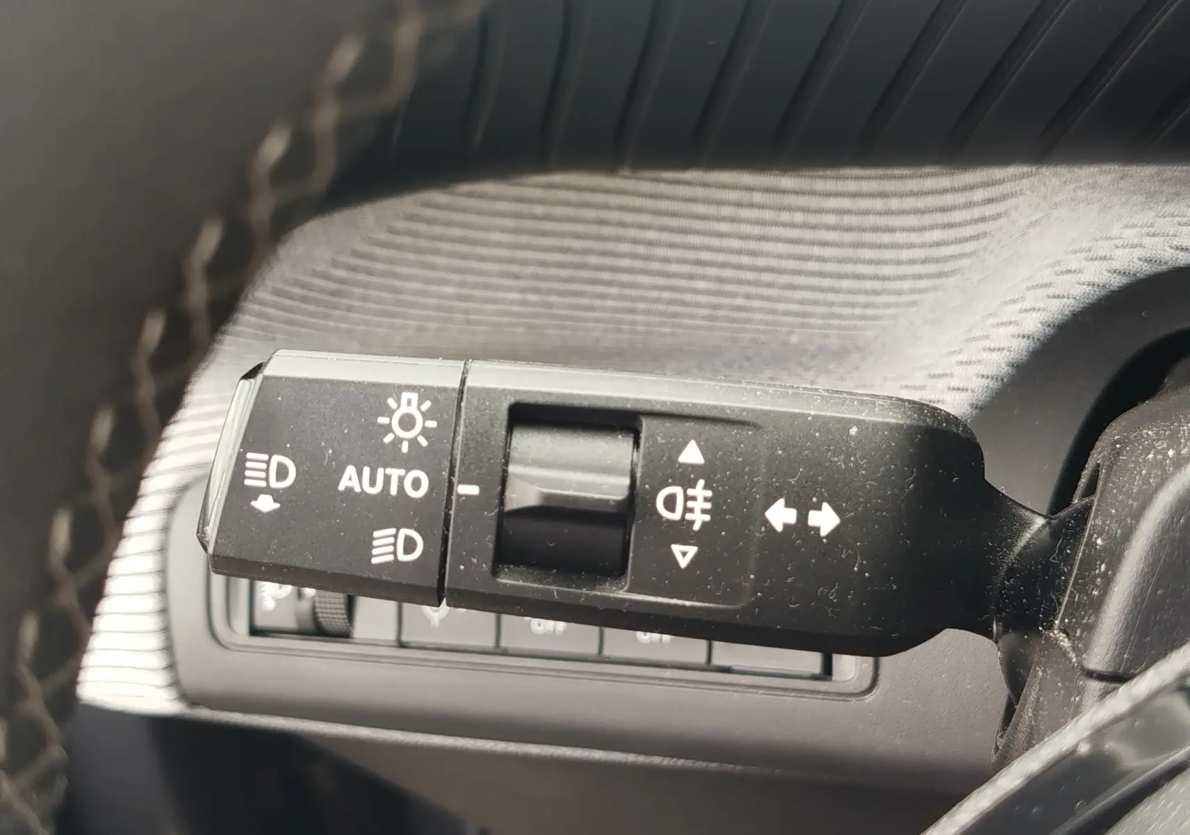 Gros plan sur la commande des feux et clignotants à gauche du volant dans l’habitacle gris foncé d’une Citroën C3 2025.