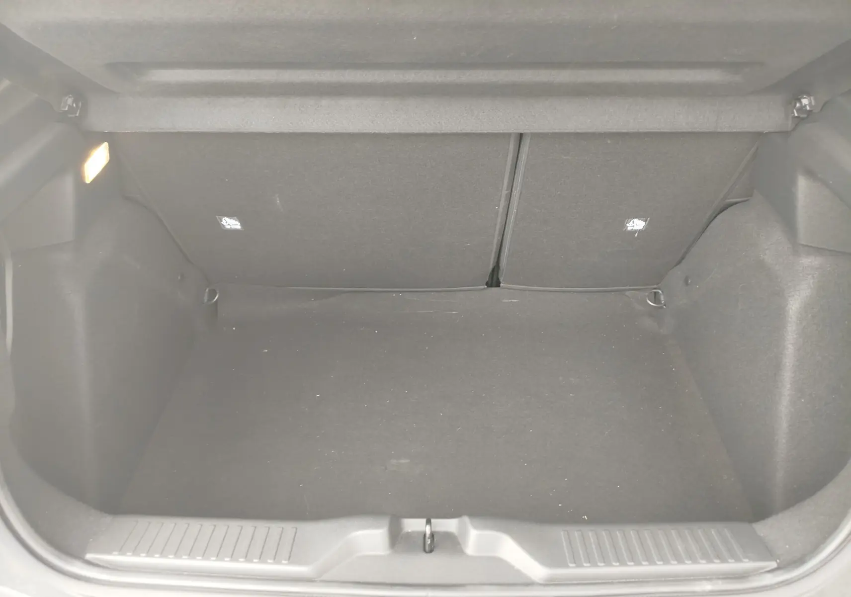 Coffre vide en tissu noir de la Citroën C3 1.2 Turbo 100ch MAX 2025, vu de l'arrière avec éclairage intérieur allumé.