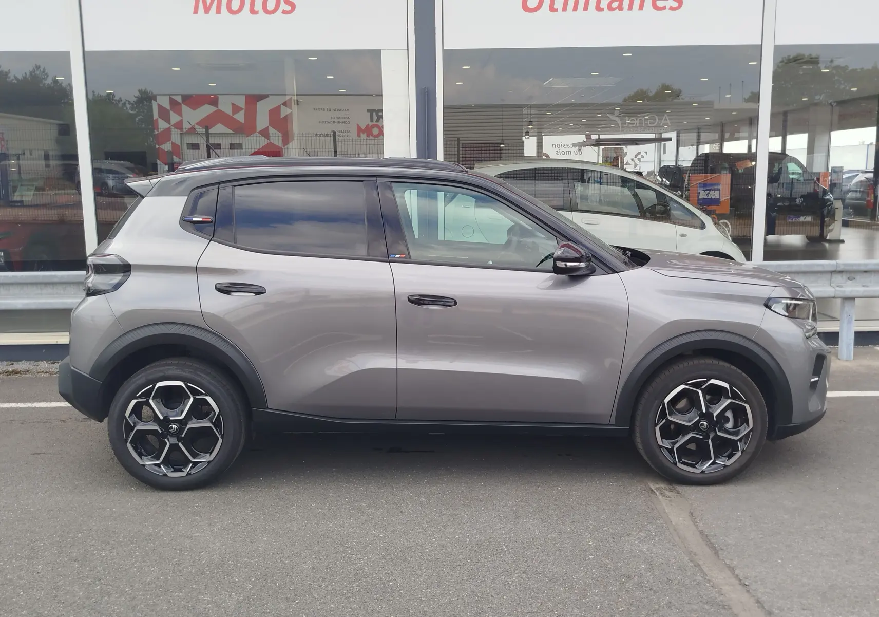 Profil droit d'une Citroën C3 1.2 Turbo 100ch gris foncé avec toit noir et jantes alliage noires, en extérieur.