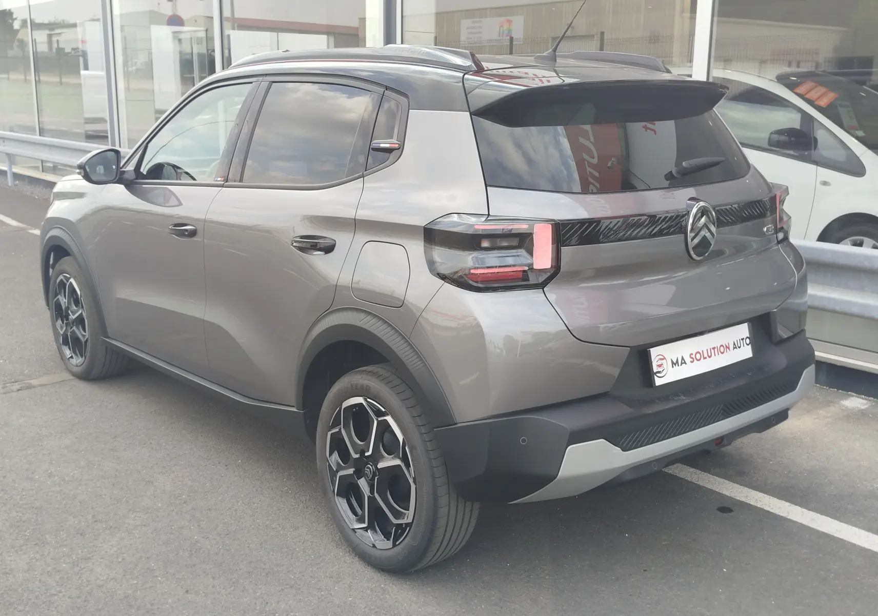 Vue 3/4 arrière droite d'une Citroën C3 2025 gris foncé avec toit noir et jantes noires bicolores.