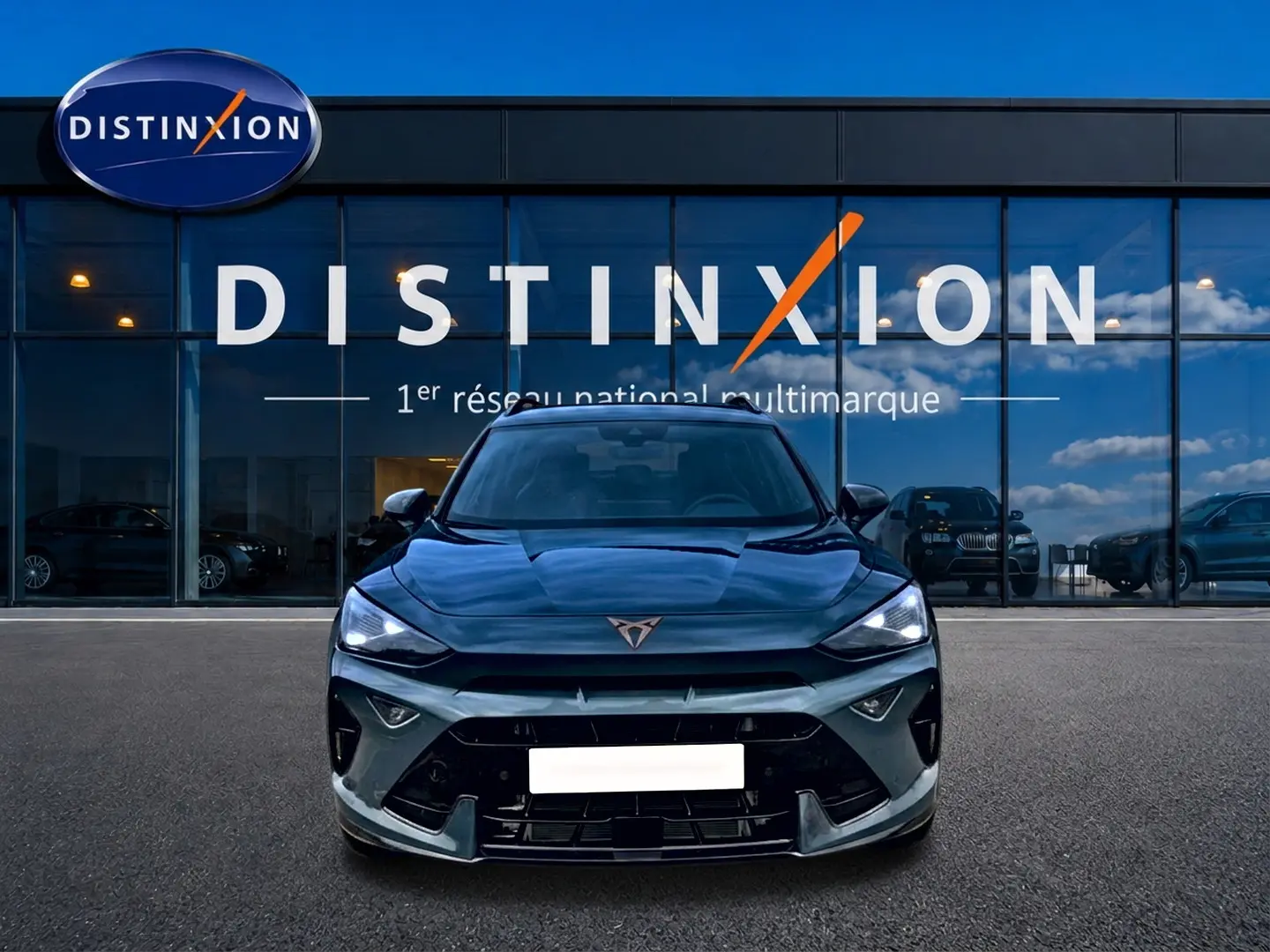 Vue frontale d'un CUPRA Formentor bleu fjord 2026 avec phares LED allumés devant une vitrine Distinxion.