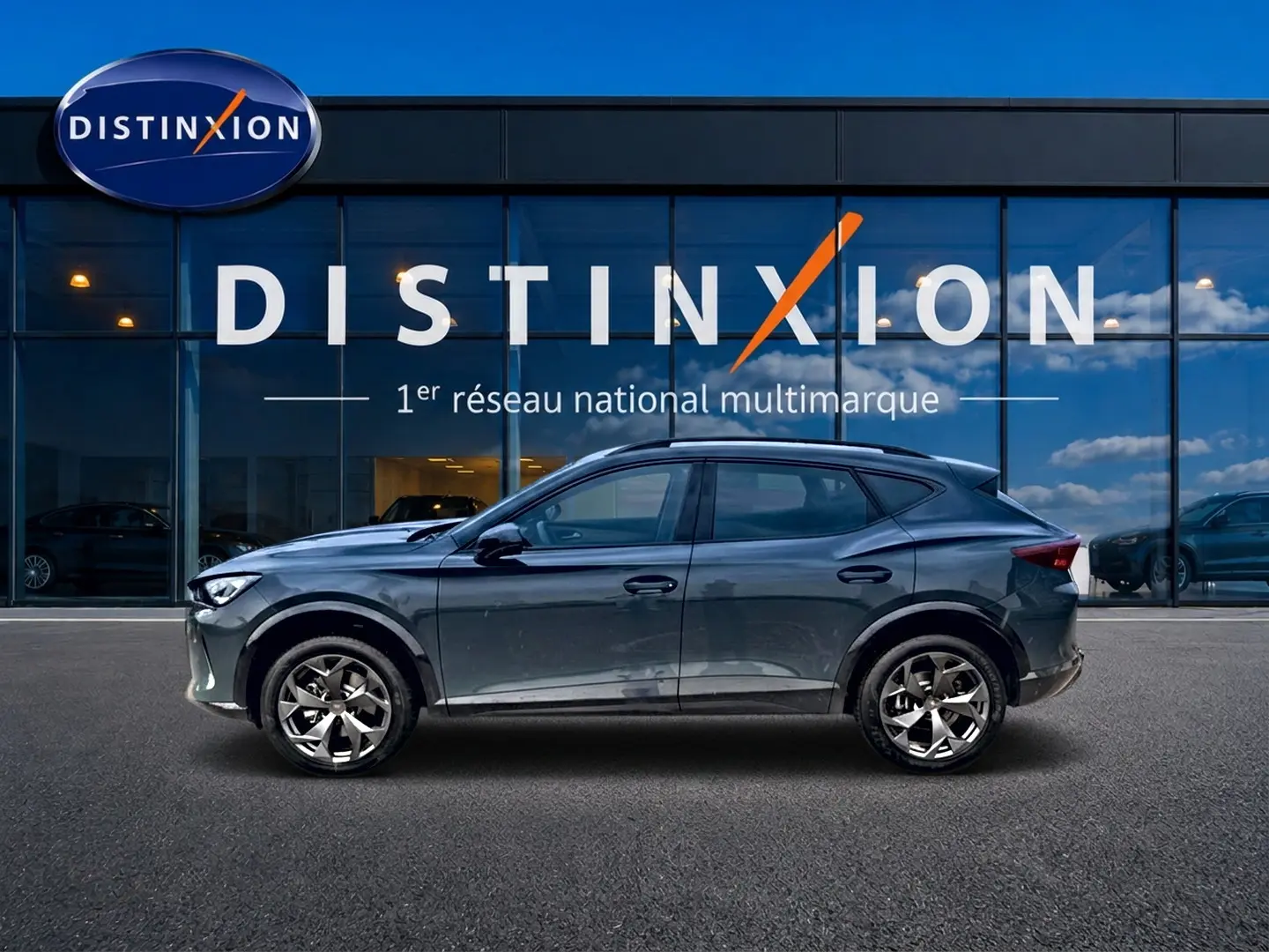 Vue de profil côté gauche du CUPRA Formentor 1.5 etsi hybrid bleu fjord avec jantes 18 pouces devant une vitrine Distinxion.