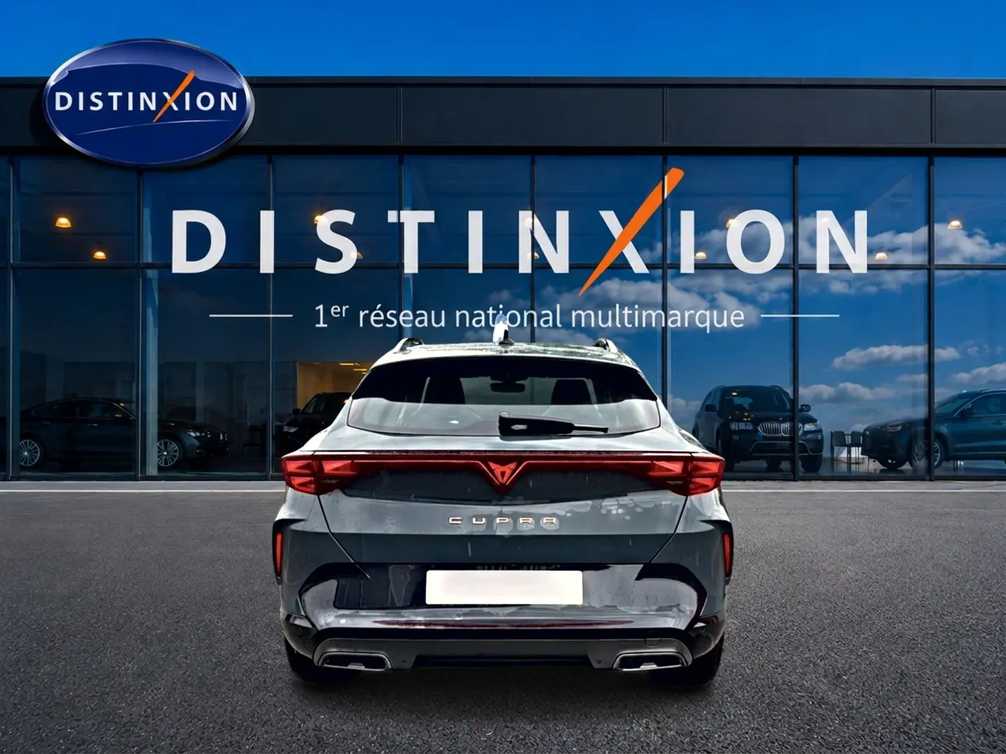 Vue arrière d'un CUPRA Formentor bleu fjord 2026 avec feux LED et double sortie d'échappement, devant un showroom Distinxion.