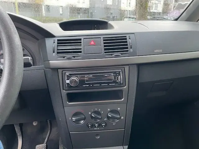 Tableau de bord central de l'Opel Meriva grise 2010 avec commandes de climatisation et autoradio visible en gros plan.