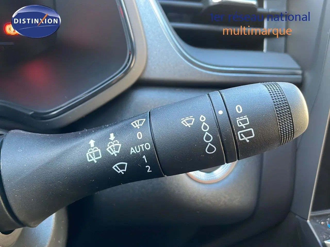 Gros plan sur la commande des essuie-glaces du tableau de bord d'un Renault Captur gris Cassiopée 2025 hybride.