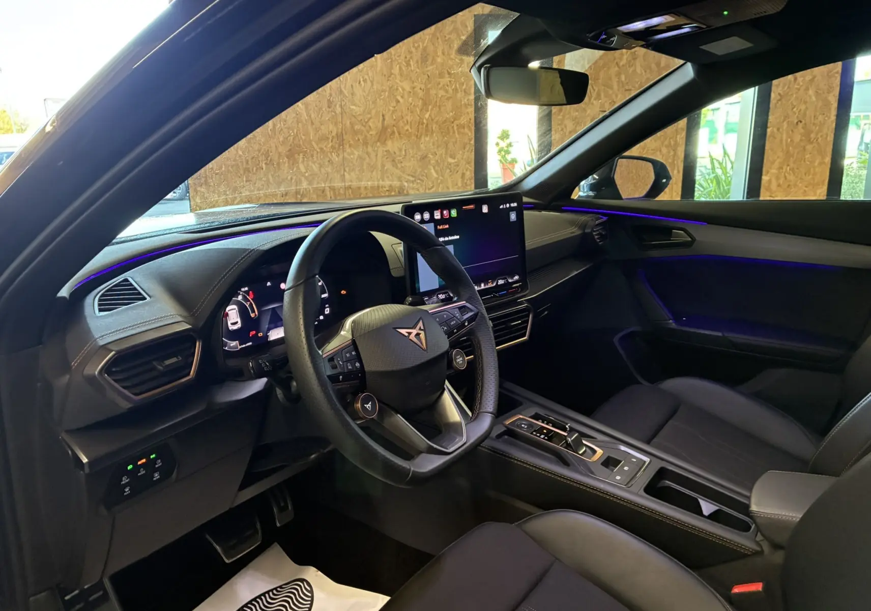 Intérieur noir du CUPRA Formentor 2024 vu côté conducteur, avec tableau de bord digital et éclairage d'ambiance violet.