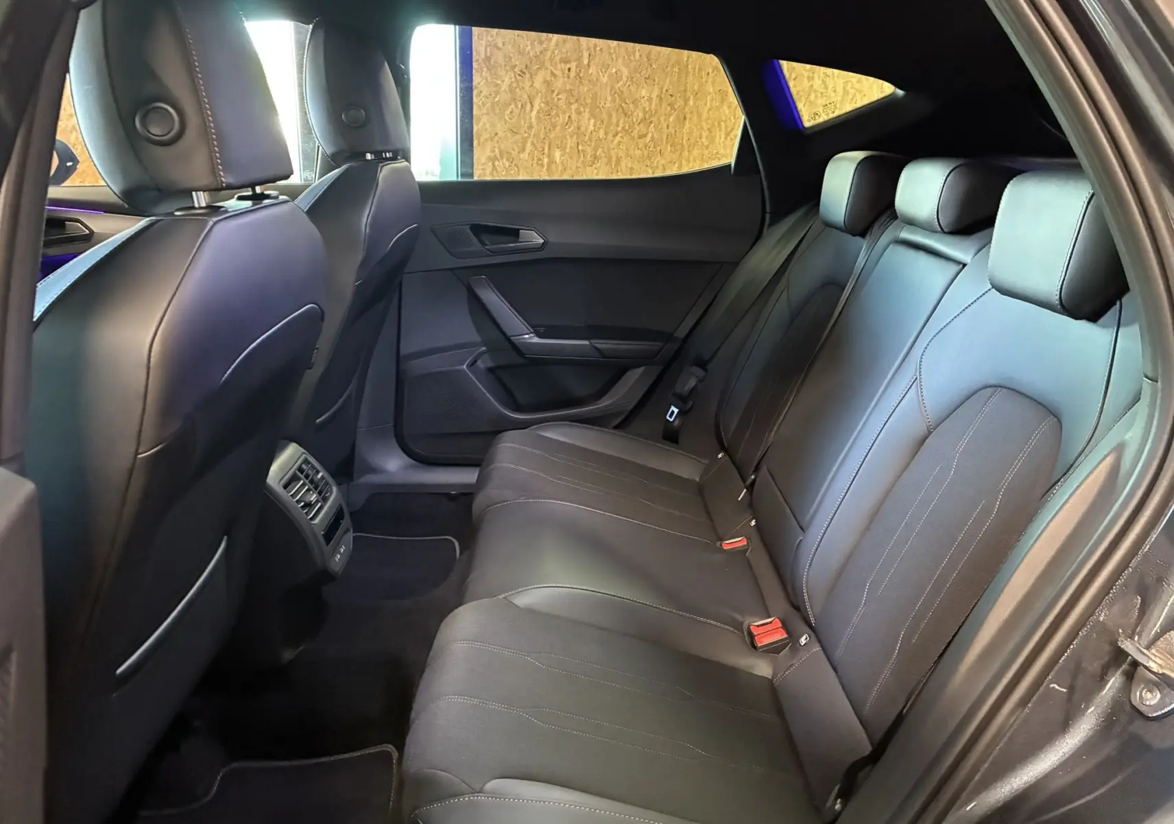 Vue intérieure du siège arrière droit en cuir noir du CUPRA Formentor gris foncé 2024, avec appuie-têtes et ceintures visibles.