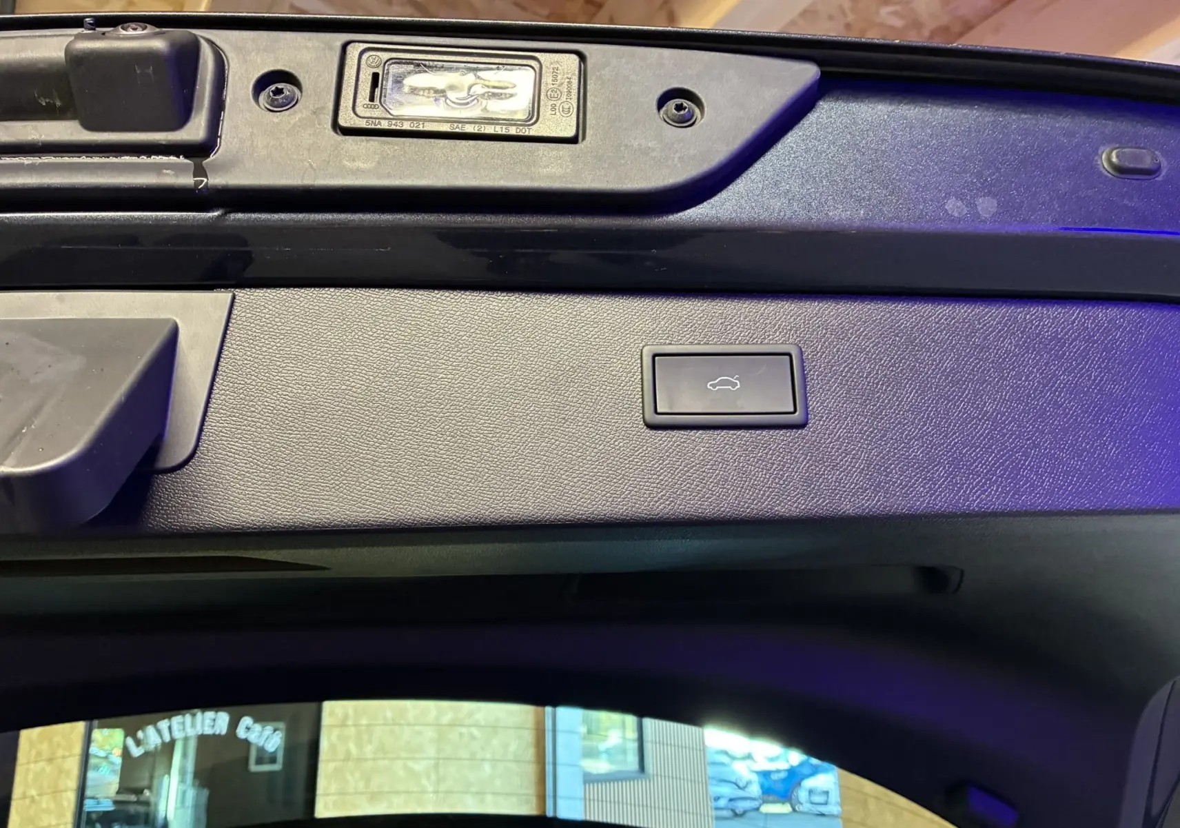 Bouton d'ouverture du coffre sur la partie intérieure de la porte arrière d'un CUPRA Formentor gris foncé, vue rapprochée.