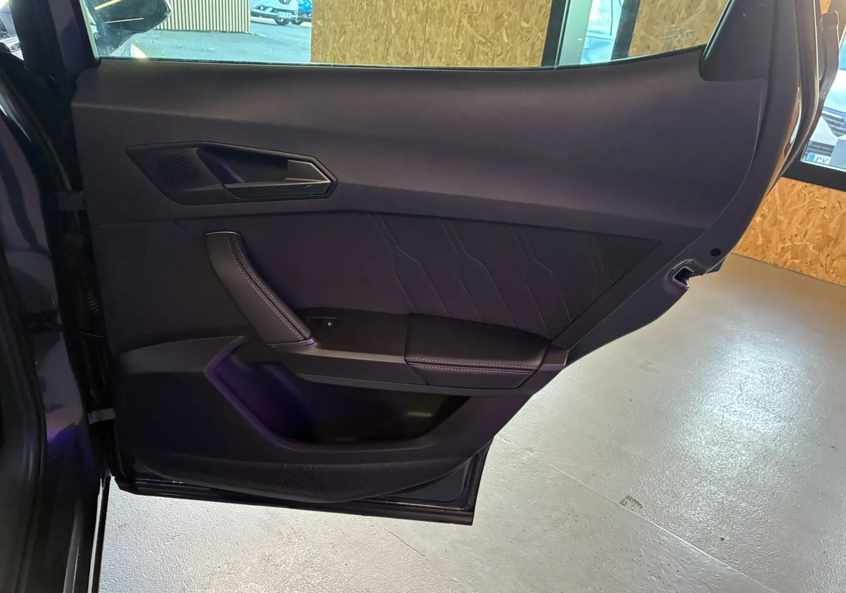 Porte arrière gauche ouverte du CUPRA Formentor gris foncé, intérieur noir avec surpiqûres et poignée intégrée.