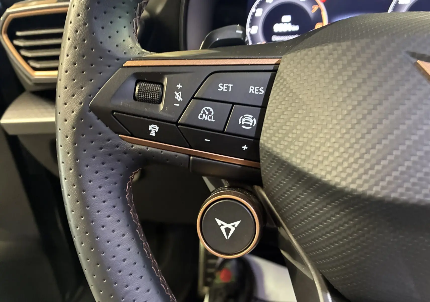 Gros plan sur la partie gauche du volant en cuir perforé gris foncé du CUPRA Formentor 2024 avec commandes intégrées.