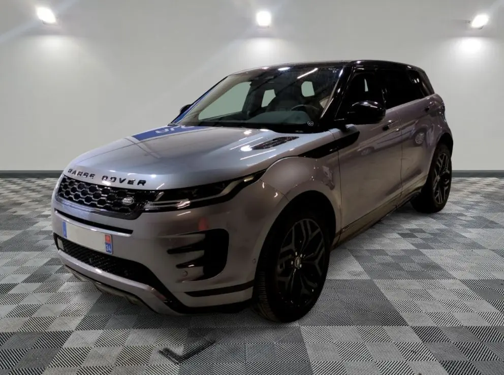 Vue 3/4 avant d'un Range Rover Evoque 200D SE R-Dynamic gris Eiger avec jantes noires, devant un showroom multimarque.
