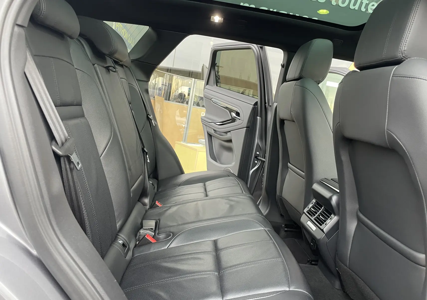 Vue intérieure arrière du Range Rover Evoque 200D SE R-Dynamic avec sièges en cuir noir et porte arrière ouverte côté droit.