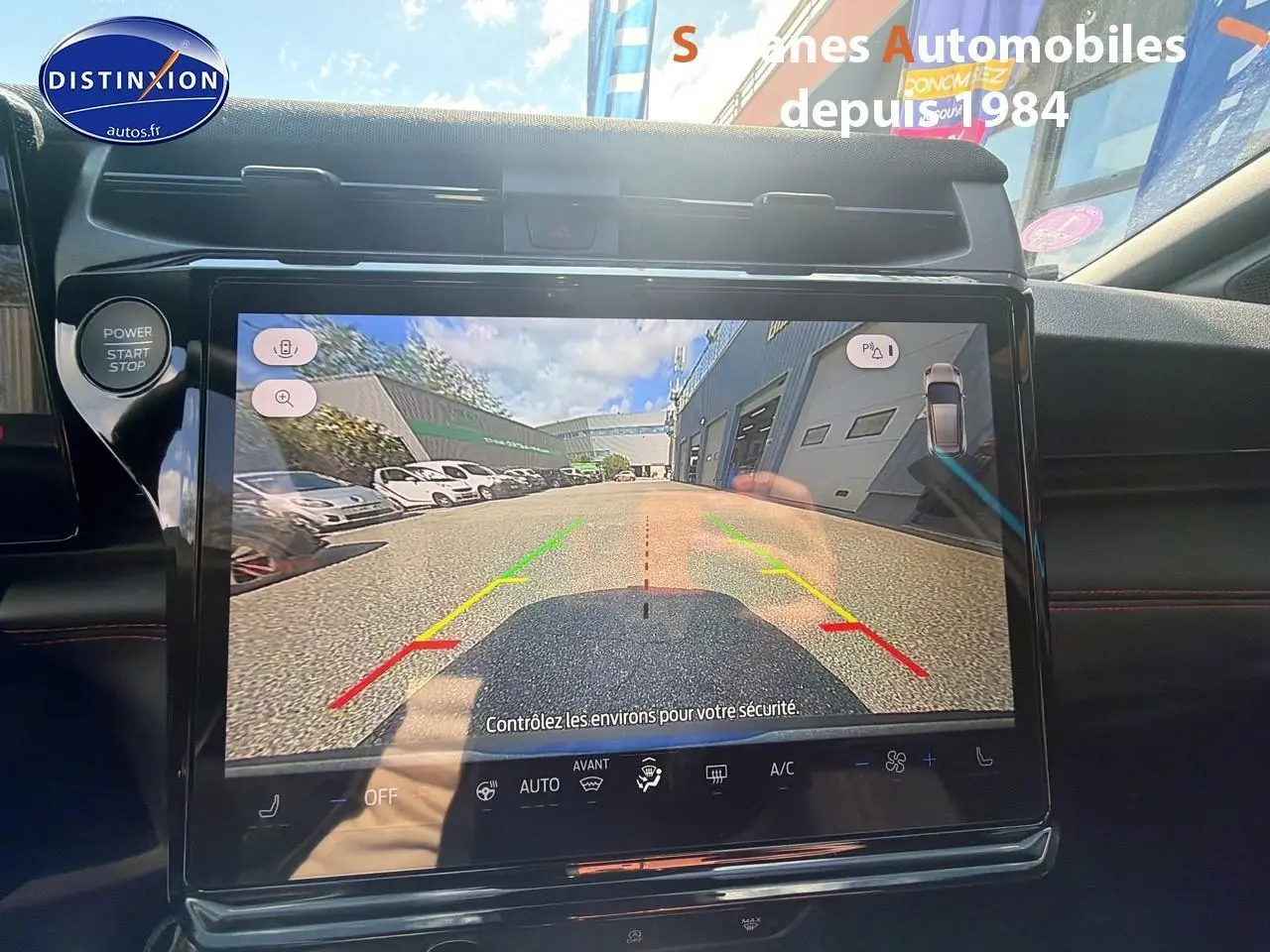 Vue intérieure sur l'écran de caméra de recul du Ford Puma bleu, avec commandes et tableau de bord visibles.