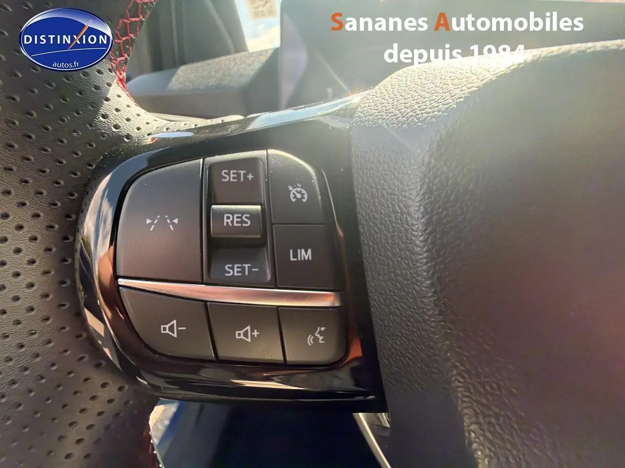 Gros plan sur les commandes de régulateur de vitesse et volume au volant perforé du Ford Puma bleu 2025 finition ST-Line.