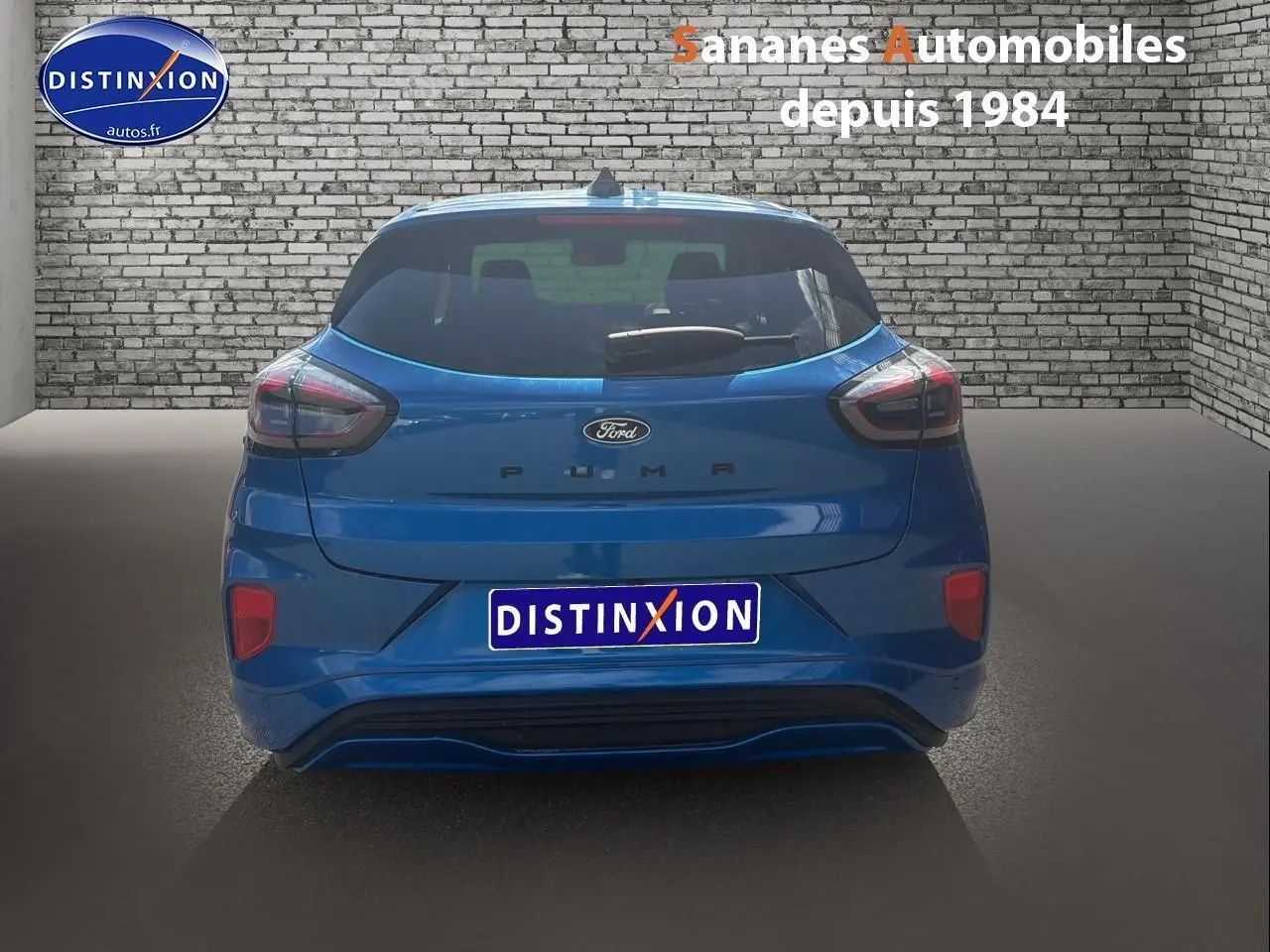 Vue arrière d'une Ford Puma bleu métallisé, avec hayon et feux arrière distinctifs dans un showroom.