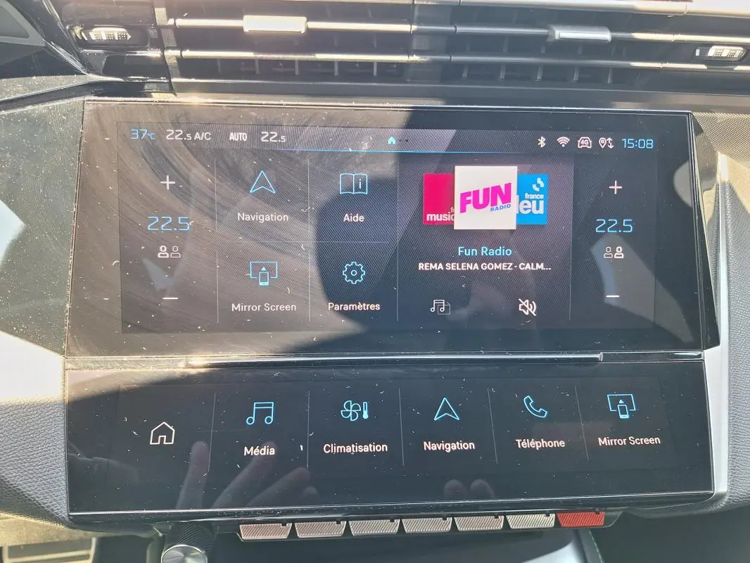 Vue rapprochée de l'écran tactile central du Peugeot 308 Hybrid 145 e-DCS6 GT 2025 avec interface multimédia et climatisation digitale.