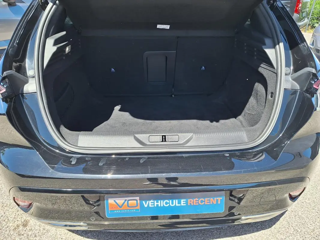 Coffre ouvert vu de l'arrière d'une Peugeot 308 Hybrid 145 e-DCS6 GT noire, montrant un espace de chargement vide.