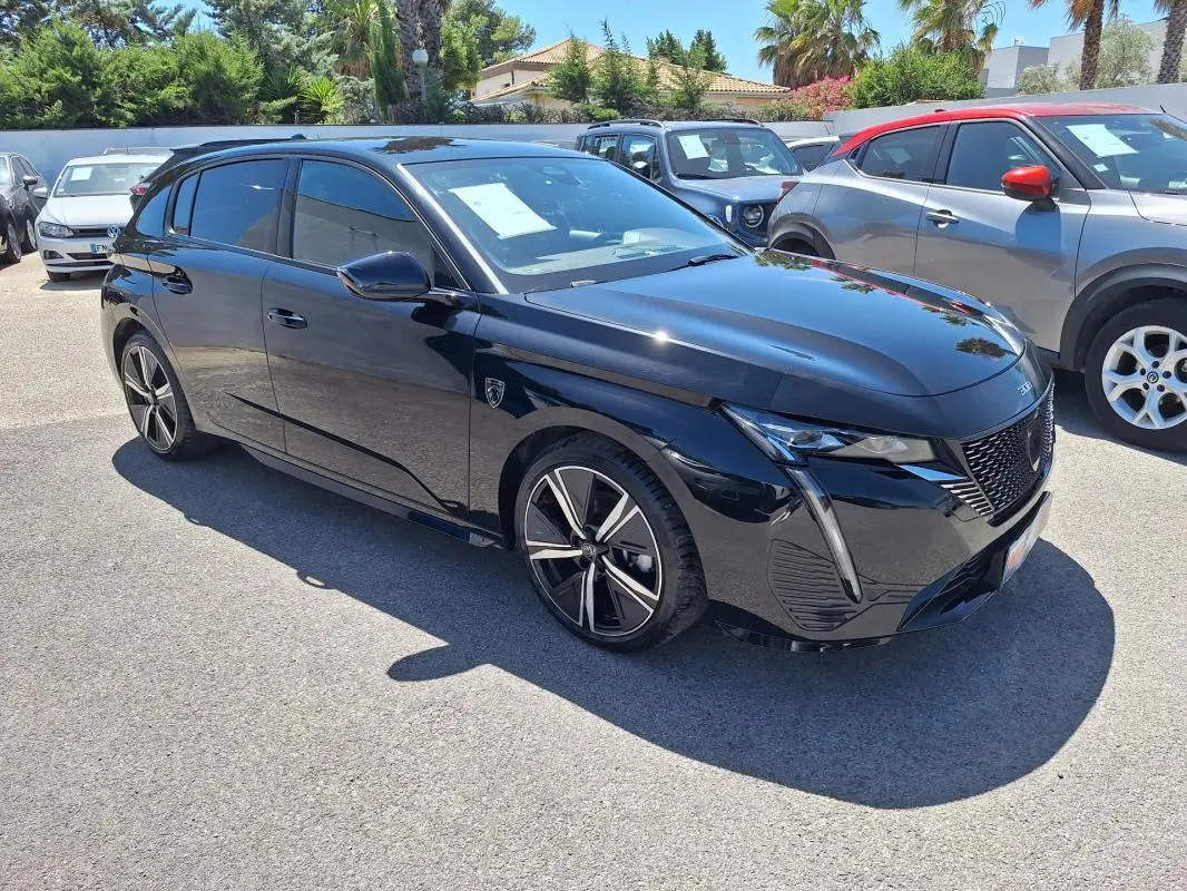 Peugeot 308 Hybrid 145 e-DCS6 GT noire vue en 3/4 avant droit, avec jantes alliage 18 pouces et vitres teintées.