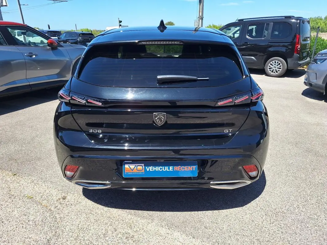 Vue arrière d'une Peugeot 308 Hybrid 145 e-DCS6 GT noire avec feux LED et double sortie d'échappement chromée.