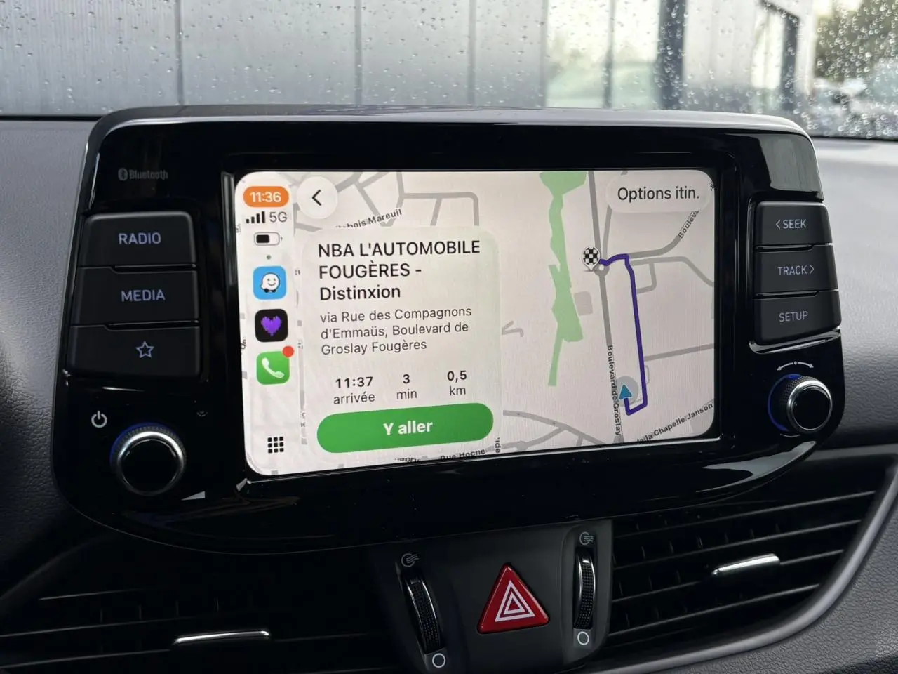 Écran tactile central de la Hyundai i30 SW T-GDI 120 Modern affichant un GPS avec itinéraire, boutons de contrôle autour.