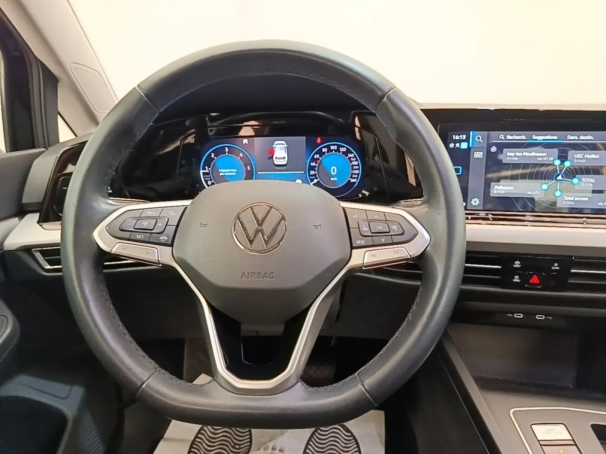 Vue intérieure centrée sur le volant cuir de la Volkswagen Golf 2023 avec tableau de bord digital et écran tactile.