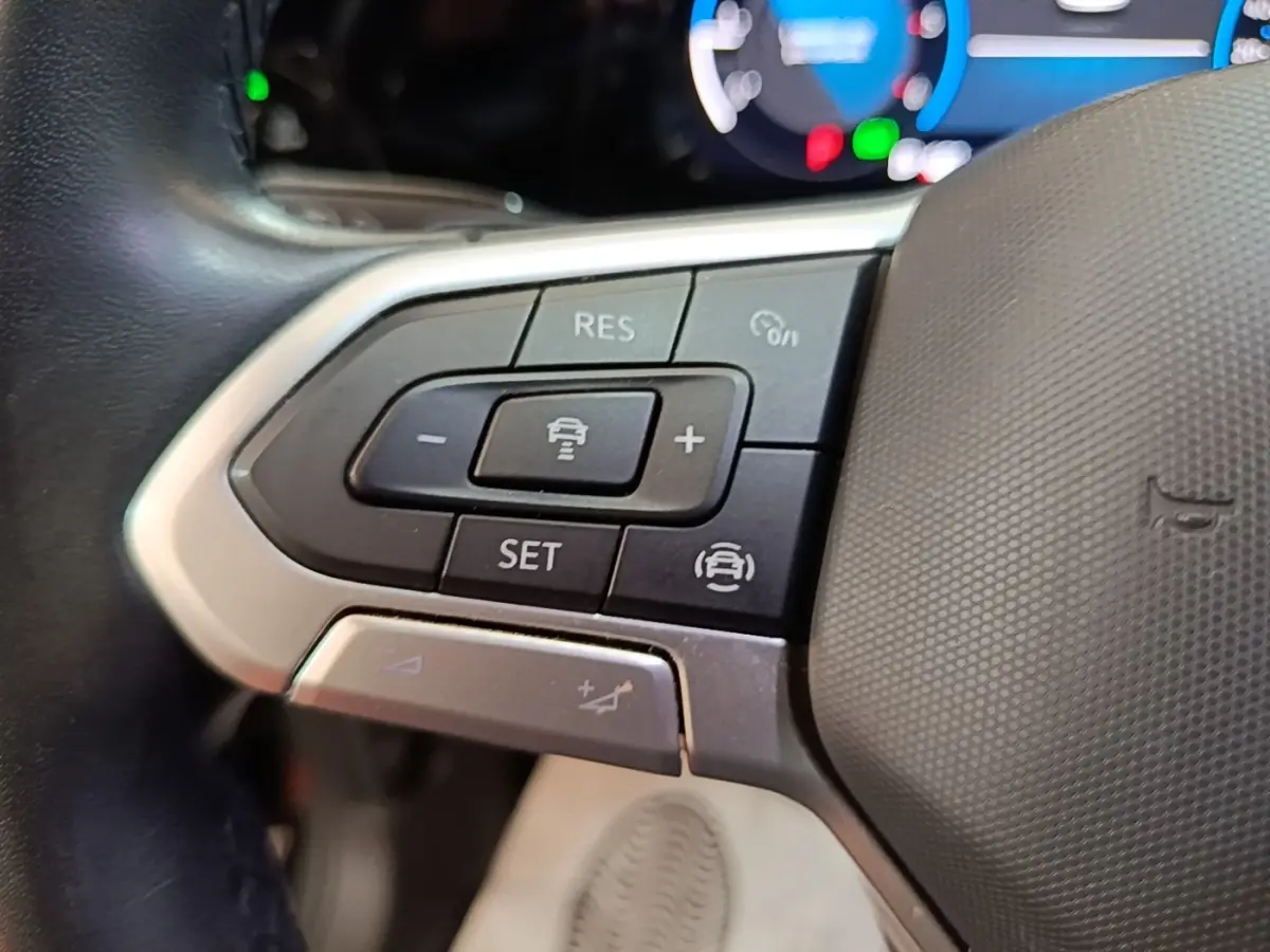 Gros plan sur les commandes du volant côté gauche de la Volkswagen Golf noire 2023 avec affichage digital en arrière-plan.
