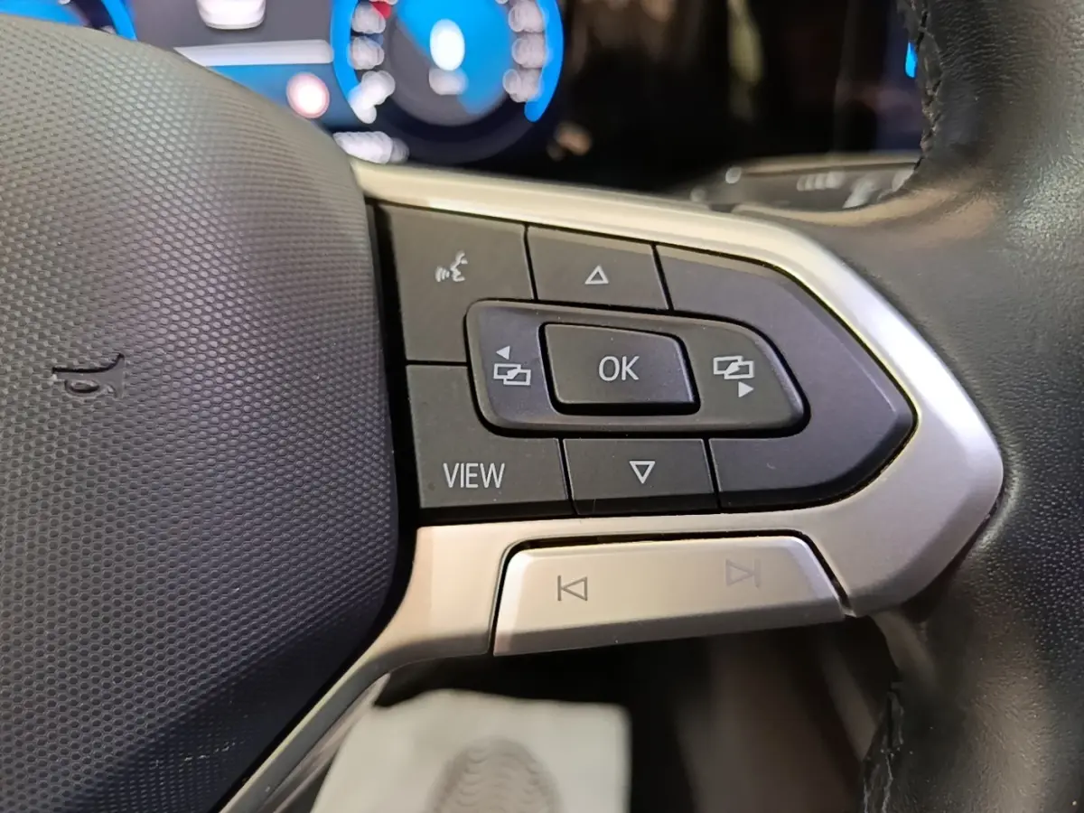 Gros plan sur les commandes multifonctions côté gauche du volant noir de la Volkswagen Golf 2023, affichage digital en arrière-plan.