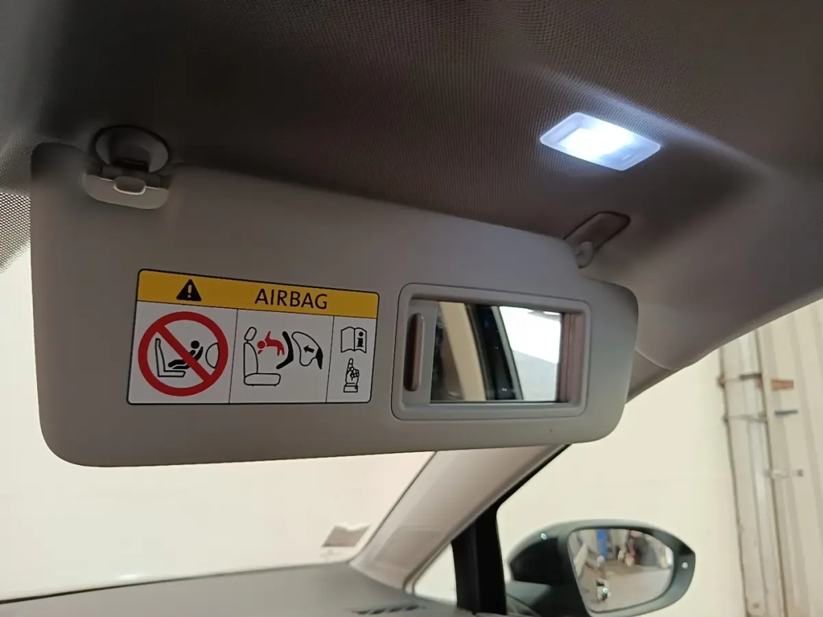 Détail du pare-soleil côté conducteur beige avec miroir et avertissement airbag, intérieur clair d'une Volkswagen Golf noire.