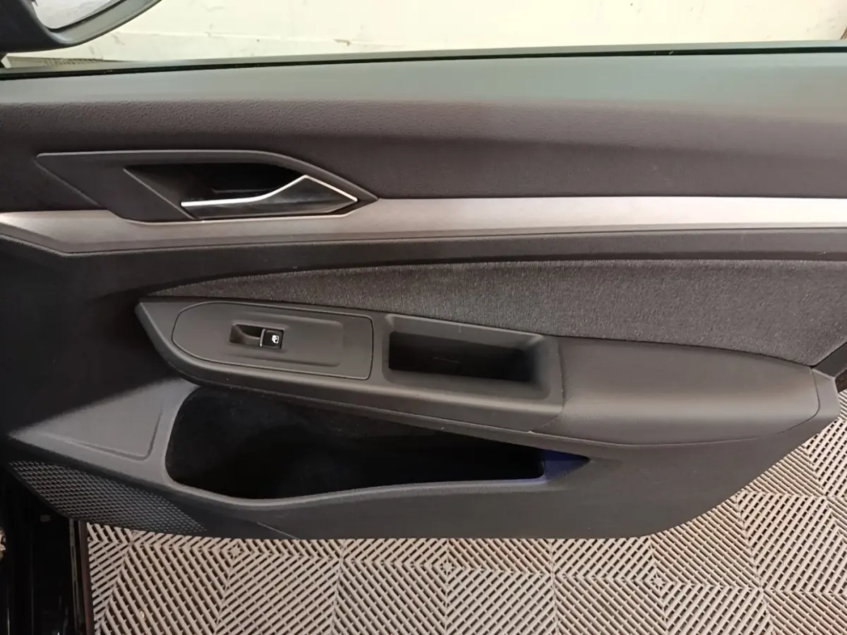 Vue intérieure du panneau de porte côté gauche noir de la Volkswagen Golf 2.0 TDI 2023 avec poignée argentée.