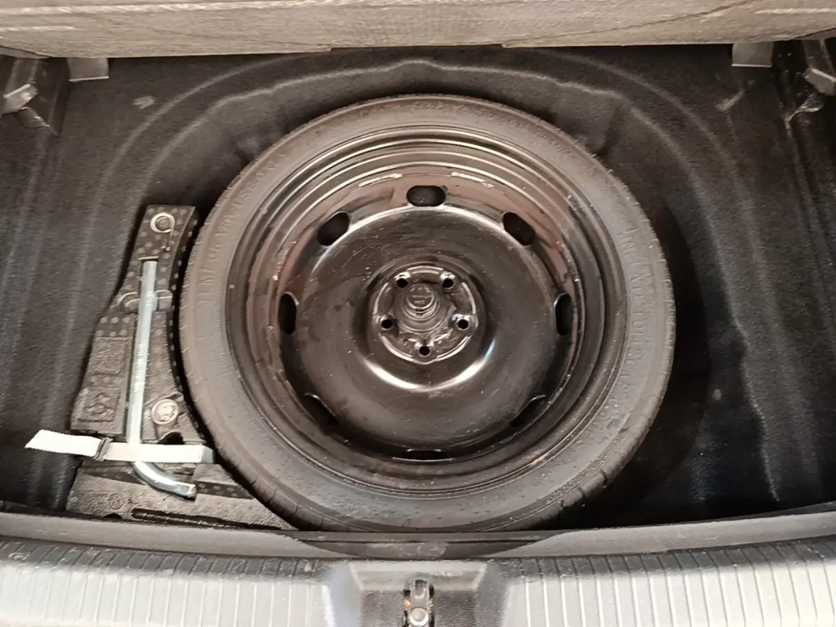 Vue rapprochée de la roue de secours galette noire dans le coffre d'une Volkswagen Golf 2023.