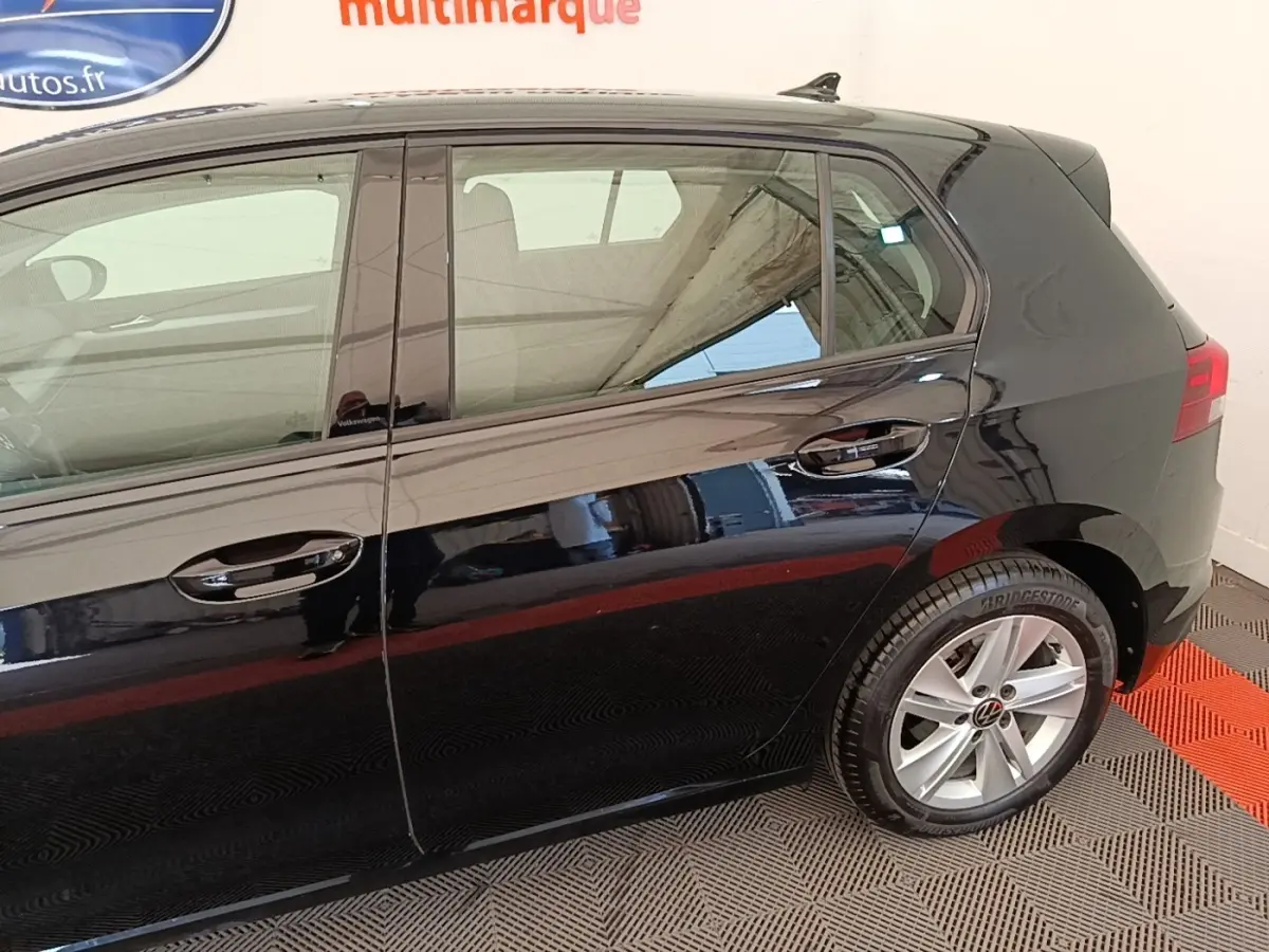 Vue latérale droite d'une Volkswagen Golf noire 2023, mettant en valeur les jantes alliage et les vitres teintées.