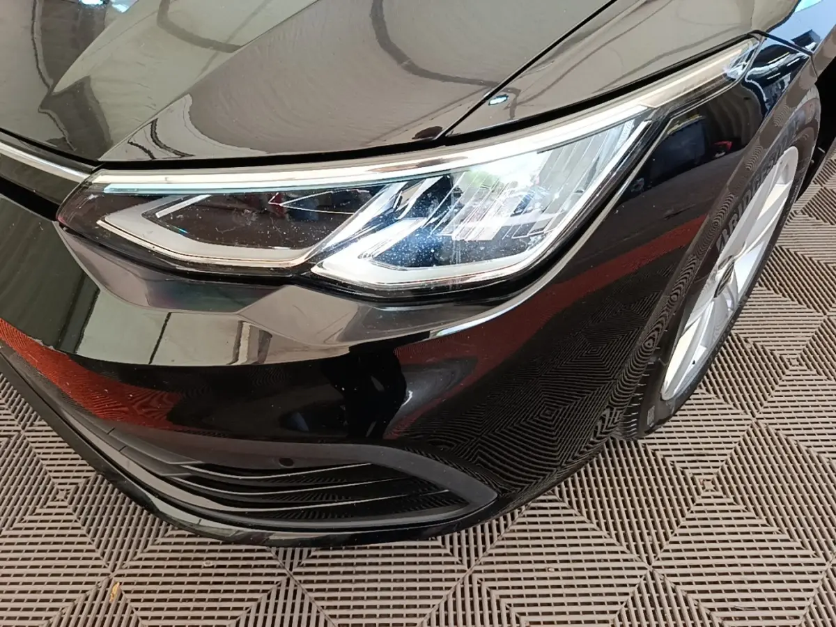 Gros plan sur le phare avant droit de la Volkswagen Golf noire 2023, mettant en valeur son design LED moderne.