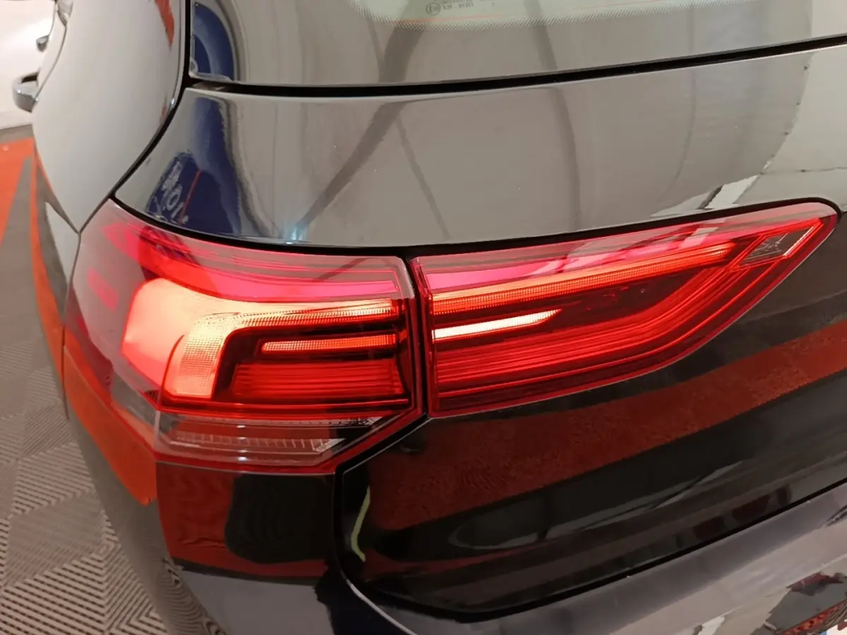 Gros plan sur le feu arrière gauche rouge d'une Volkswagen Golf noire 2023, vue depuis l'arrière côté gauche.