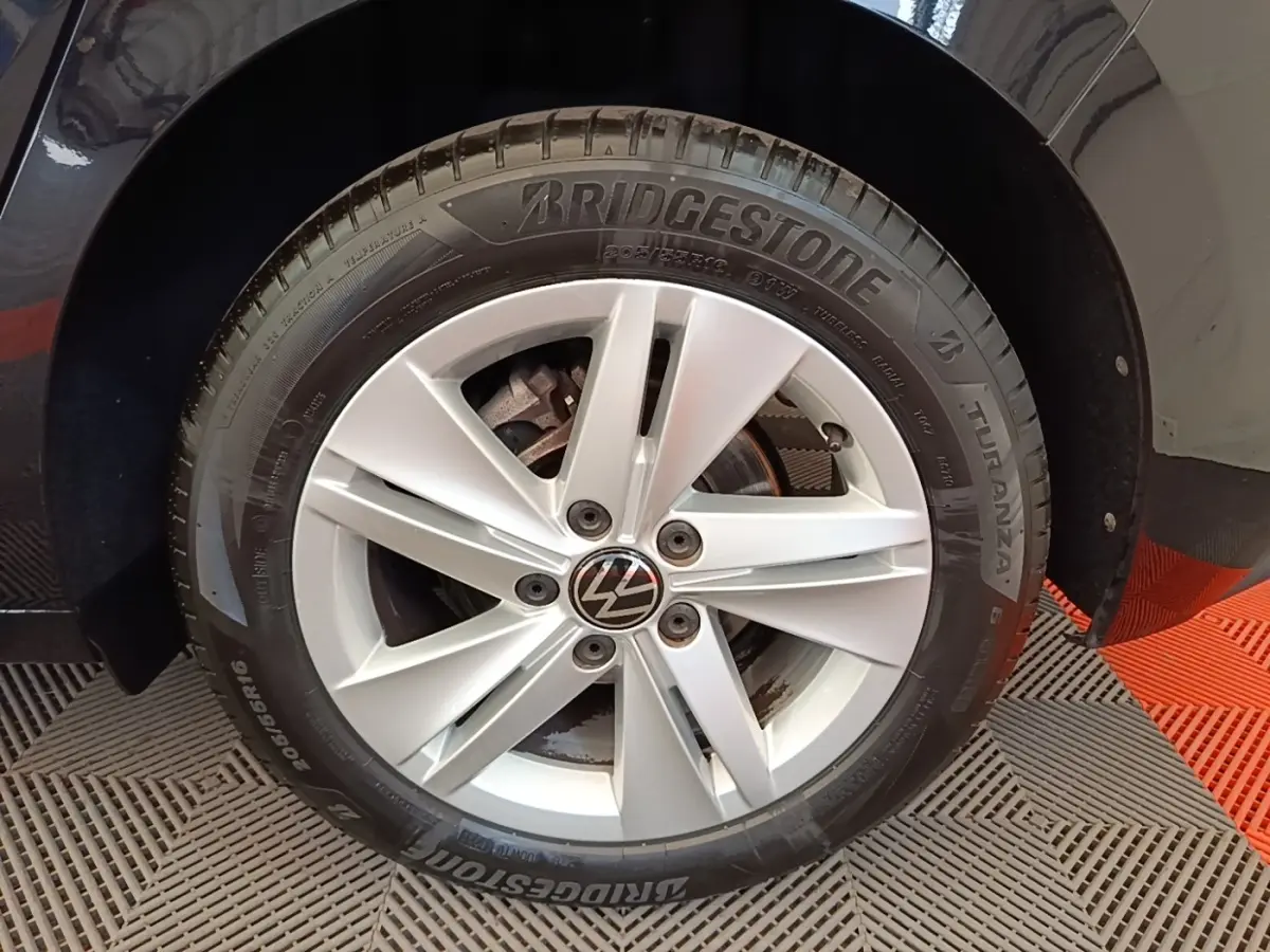Gros plan sur la roue avant droite d'une Volkswagen Golf noire avec jante alliage argent et pneu Bridgestone.