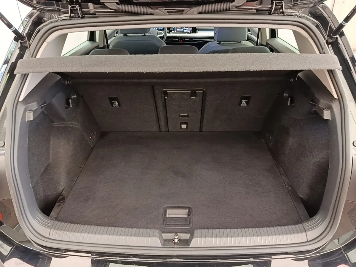 Vue arrière du coffre ouvert d’une Volkswagen Golf noire 2023, montrant l’espace de chargement vide et la tablette cache-bagages.