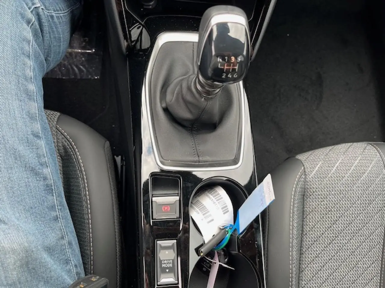 Vue plongeante sur la console centrale du Peugeot 2008 blanc, mettant en valeur le levier de vitesses manuel et les sièges avant.