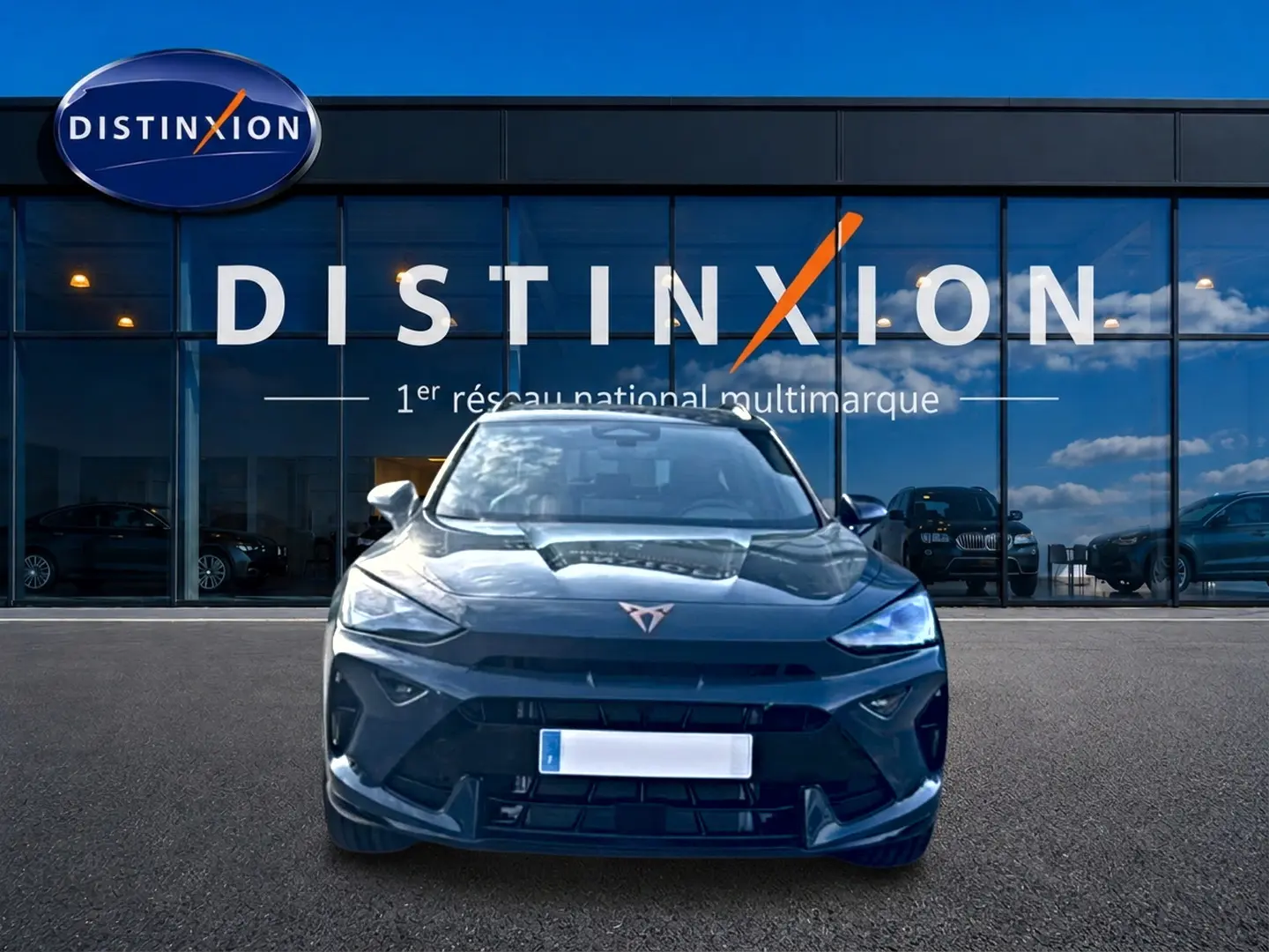 Vue frontale d'un CUPRA Formentor bleu fjord 2026, avec calandre marquée et logo distinctif sur fond de vitrine Distinxion.