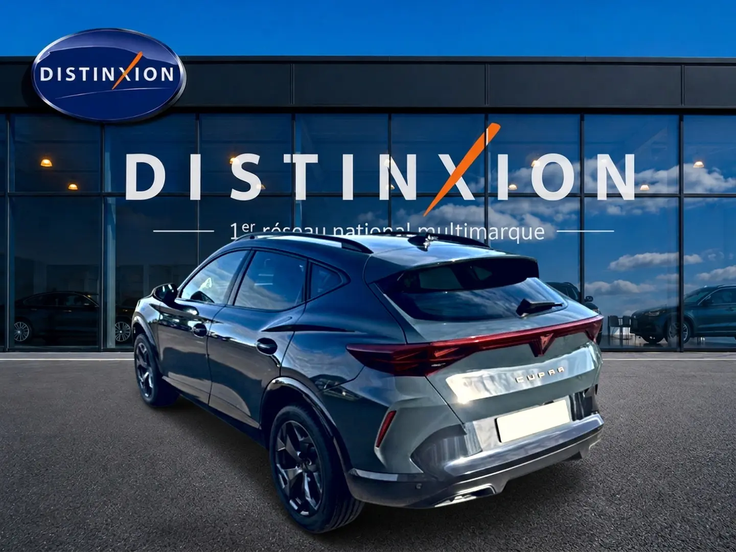 Vue 3/4 arrière droite du CUPRA Formentor bleu fjord 2026 avec feux arrière LED et jantes 18 pouces devant un showroom Distinxion.