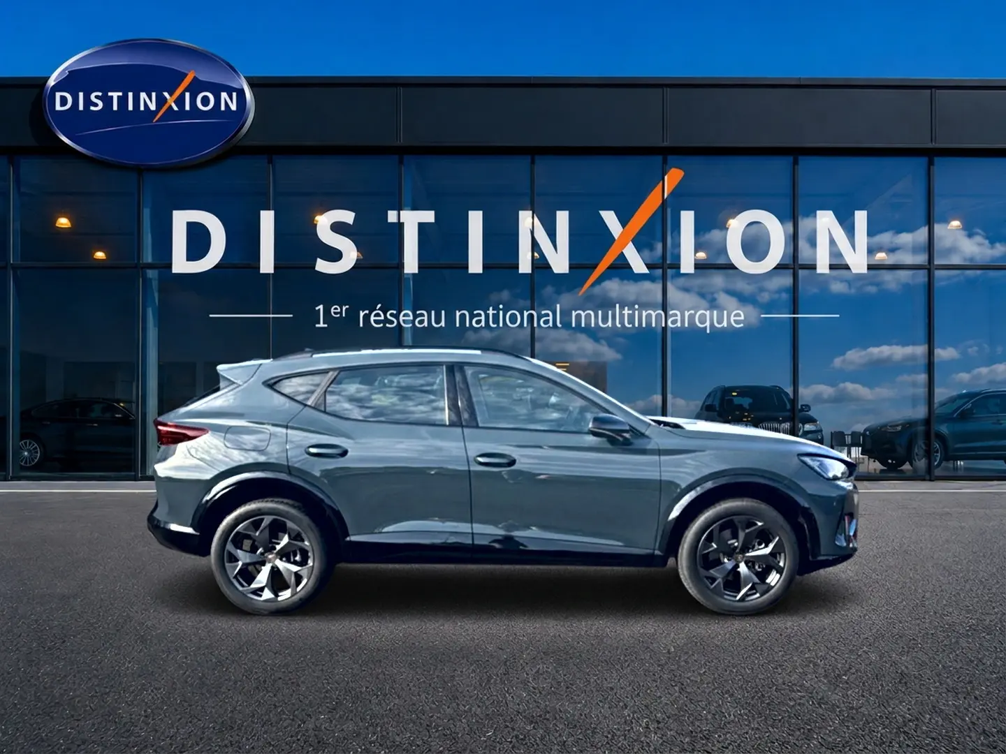 Vue latérale droite d'un CUPRA Formentor bleu fjord 2026 avec jantes 18 pouces devant une vitrine Distinxion.