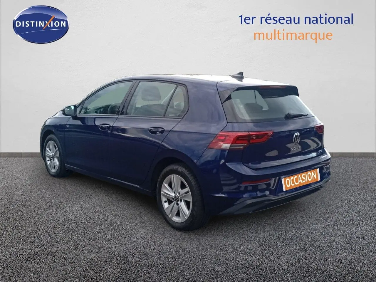 Volkswagen Golf VIII bleu Atlantique métal vue 3/4 arrière côté gauche sur sol gris devant un mur blanc.