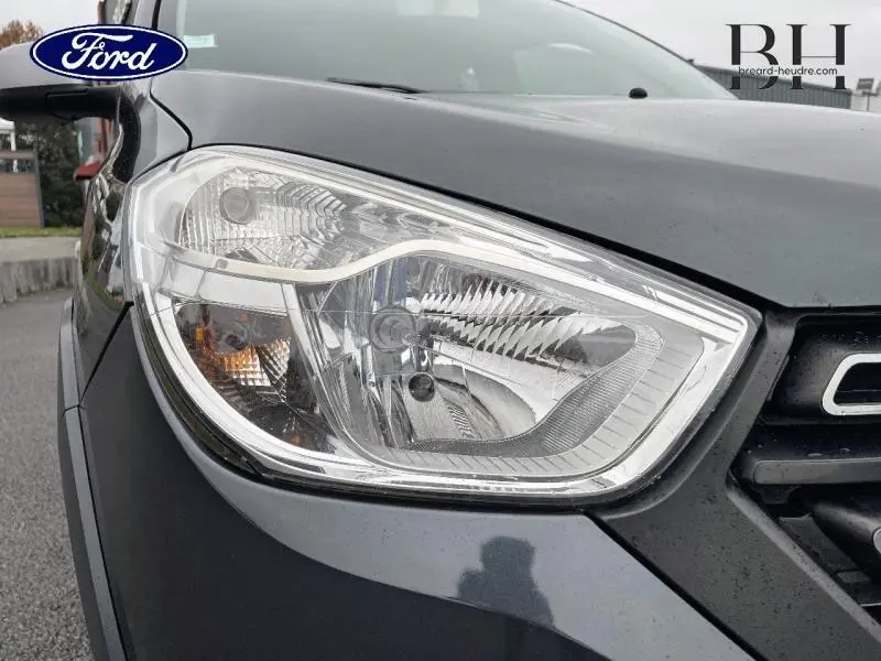 Gros plan sur le phare avant droit du Dacia Lodgy gris Comète 2020, mettant en valeur le design lumineux et la calandre partielle.