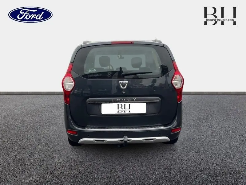 Vue arrière d'un Dacia Lodgy gris foncé avec hayon, feux verticaux et attelage de remorque visible.
