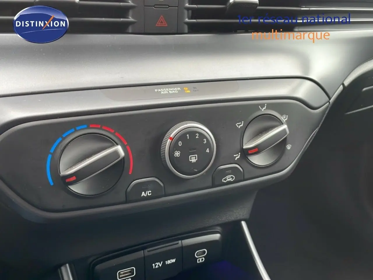 Gros plan sur les commandes de climatisation et prises USB dans l'habitacle noir du Hyundai i20 2025 vert Mangrove.