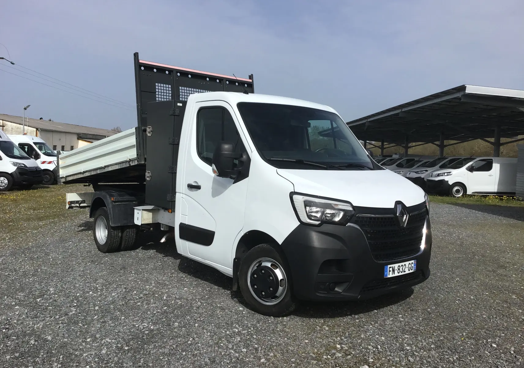 Renault Master Châssis cabine blanc en 3/4 avant droit, avec benne basculante et grille de protection noire.